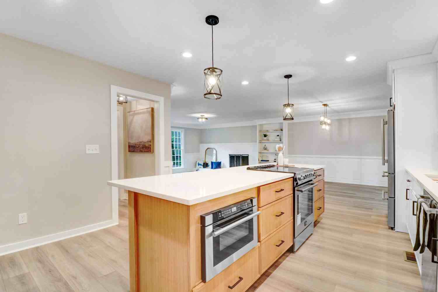 Remodeled kitchen with an island, white cabinetry and pendant lighting by Green Hill Contracting